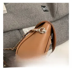 Detailed macro view of the silver metal hook and chain strap on a brown leather bag