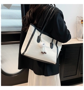 Detail shot of a large contrast canvas tote bag worn on shoulder by a model