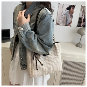 Dettaglio della borsa tote in paglia intrecciata con etichetta in pelle nera