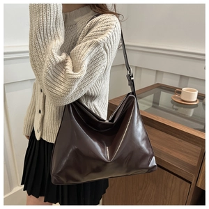 Détail d'un sac cabas en cuir brillant marron foncé avec bandoulière réglable sur mannequin