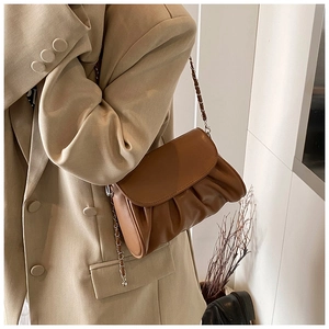Close-up of brown pleated cloud bag with elegant metal chain strap on a blazer