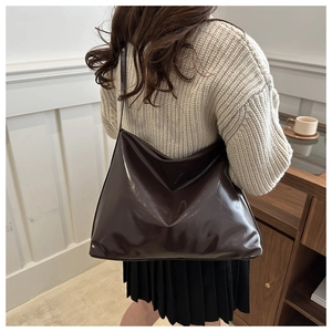 Sac fourre-tout marron foncé brillant porté avec un pull en maille et jupe noire