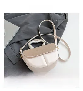 Detail of cream saddle bag with textured khaki flap and unique silver metal handle