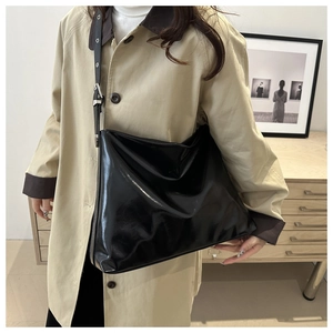 Sac cabas en cuir verni noir avec boucle argentée porté avec un trench-coat beige