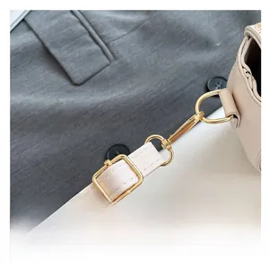 Close-up of adjustable cream leather shoulder strap with polished gold metal hardware