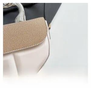 Detail of cream leather and brown woven fabric with a sleek silver metal handle