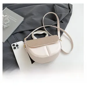 Detail of cream saddle bag with textured gold stripes and artistic metal handle