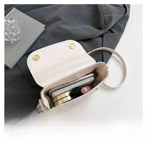 Detail view showing interior capacity of a chic semi-circle crossbody bag with daily essentials
