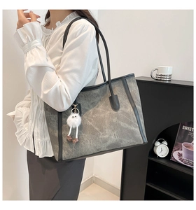 Detail view of large grey vintage tote bag with contrast black trim and fluffy monster charm