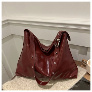 Détail du sac cabas bordeaux foncé avec texture en cuir brillant et boucles argentées