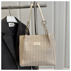 Close-up of woven straw tote bag featuring V-shaped texture and metal chain strap