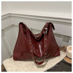 Détail du sac cabas en cuir verni bordeaux montrant la texture et les œillets argentés