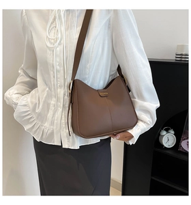 Détail du sac seau en cuir marron foncé avec coutures verticales et étiquette dorée