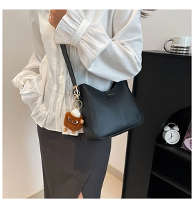 Détail du sac seau noir avec lettres dorées et pendentif de monstre en peluche marron