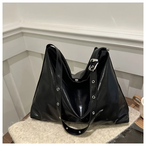 Détail du sac cabas noir brillant avec bandoulière à œillets métalliques réglable