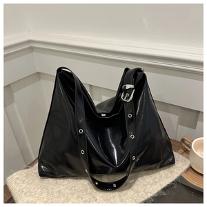 Vue détaillée du grand sac cabas noir brillant avec œillets métalliques sur la bandoulière