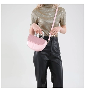 Detail view of a pink saddle bag with sequined flap and silver handle on a model