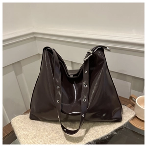 Détail du sac cabas brillant marron foncé avec bandoulière à œillets métalliques