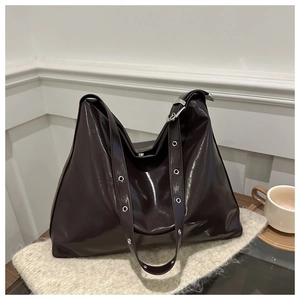 Sac fourre-tout en cuir brillant marron foncé avec œillets argentés sur un plaid