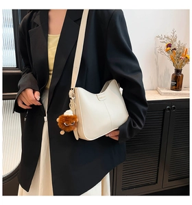 Détail du sac seau Hobo blanc cassé avec logo fashion et pendentif boule peluche
