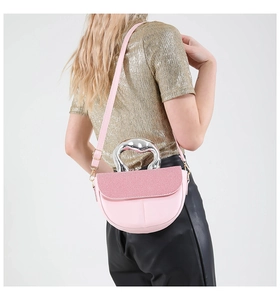 Close-up of pink crescent handbag featuring unique silver metal handle and woven texture