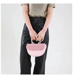 Detailed shot of pink saddle bag with a modern twisted silver metal handle accessory