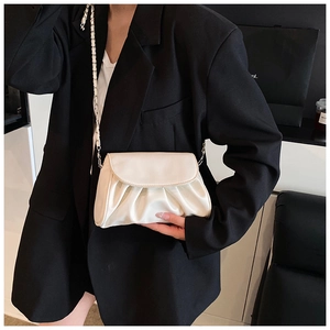 Close-up of cream white pleated cloud bag with shiny leather texture and silver chain strap