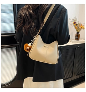 Détail d'un sac à bandoulière croissant beige crème avec un charmant ours en peluche