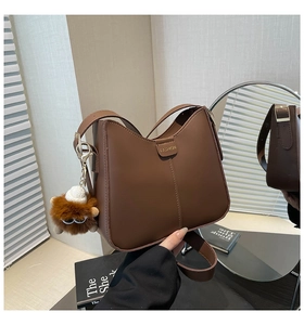 Détail d'un sac seau marron avec étiquette tendance et breloque lion en peluche