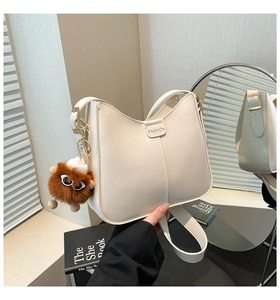 Détail d'un sac à bandoulière blanc crème avec logo FASHION et pendentif monstre mignon