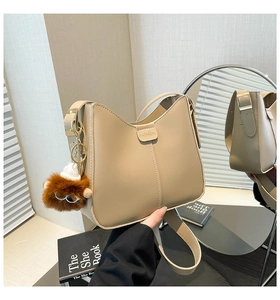 Détail du sac seau beige avec coutures verticales et breloque peluche décorative
