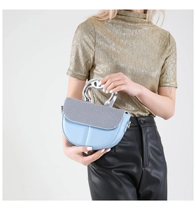Detail of light blue saddle bag with woven texture flap and unique silver metal handle