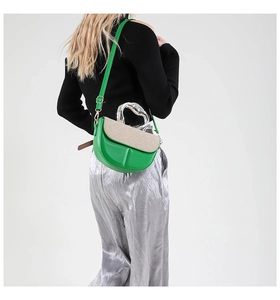 Detail of green leather and beige woven saddle bag with stylish silver metal handle