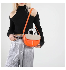 Detail of orange crossbody bag with woven flap and silver-tone metallic handle