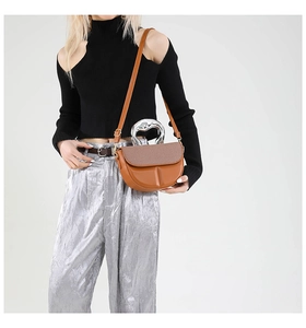 Detail of caramel saddle bag with heart-shaped silver metal handle and lychee leather