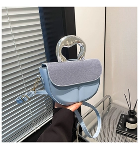 Detail der hellblauen Satteltasche mit silbernem Metallgriff und gestreifter Klappe