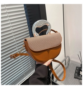 Detail einer braunen Satteltasche mit gewebter Klappe und markantem Silber-Metallgriff