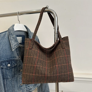 Braune Tote Bag mit Hahnentritt-Muster aus Tweed aufgehängt neben einer modischen Jeansjacke