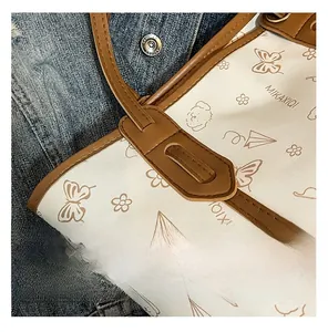 Close-up of canvas tote bag with hand-drawn illustrations and brown leather straps