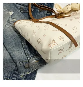Close-up of cream tote bag with brown dog illustrations and leather shoulder straps