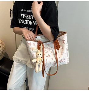 Detail of white tote bag with cartoon prints and a cute plush rabbit pendant charm