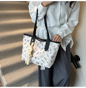 Detail of white tote bag with black hand-drawn prints and a cute plush bunny charm