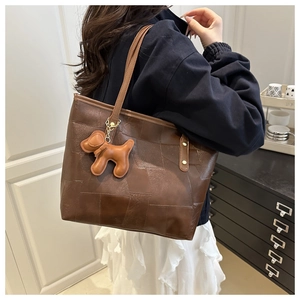 Détail du grand sac cabas marron foncé avec texture matelassée et breloque chiot