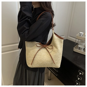 Detail view of woven straw tote bag with brown ribbon bow and large interior capacity