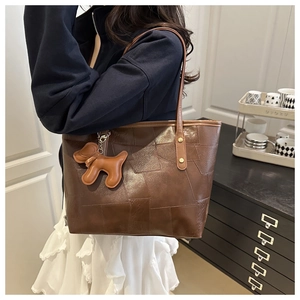 Detail of vintage brown tote bag with geometric leather patchwork and dog charm