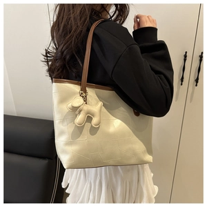 Détail du grand sac cabas crème avec coutures géométriques et breloque chien