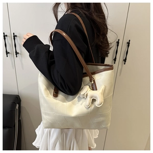 Détail du sac cabas crème avec texture gaufrée carrée et breloque en forme de chien