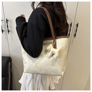 Vue détaillée du grand sac cabas crème avec coutures contrastées et charm de sac chien