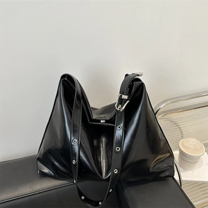 Sac fourre-tout en cuir verni noir avec bandoulière à œillets argentés et look chic