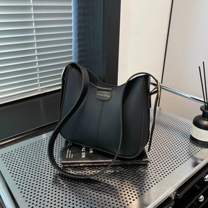 Sac seau minimaliste en cuir noir avec lettrage doré sur présentoir en métal